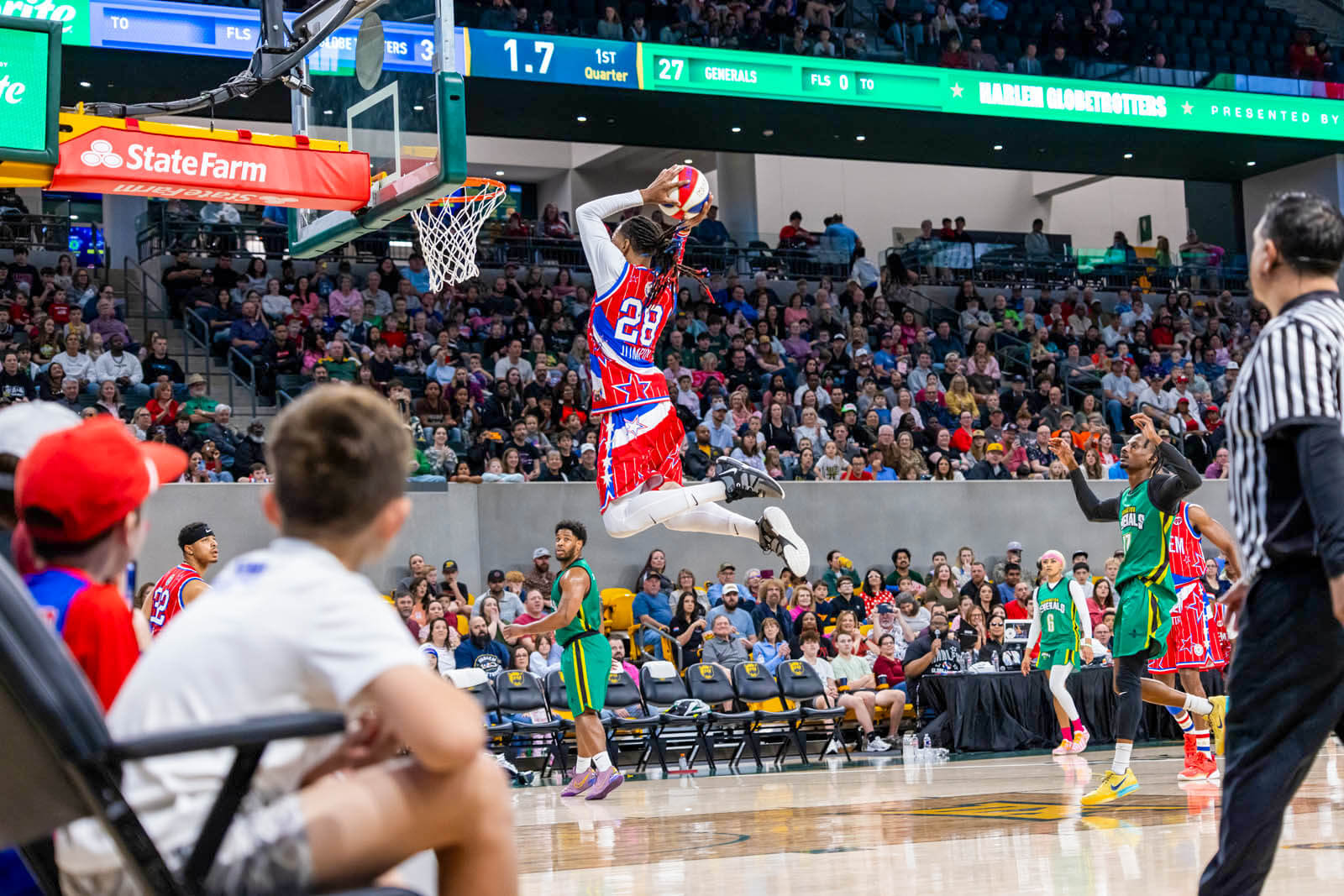 A Harlem Globetrotter dunks a basketball while fan look on