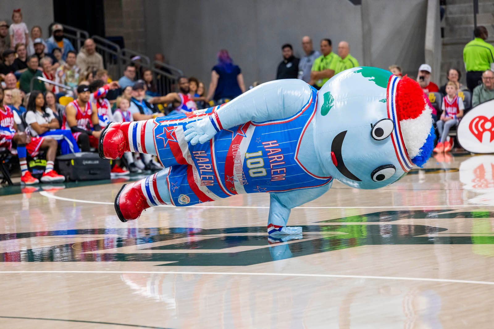 Harlem Globetrotter mascot, Big G, balances one hand as he spins around on the court