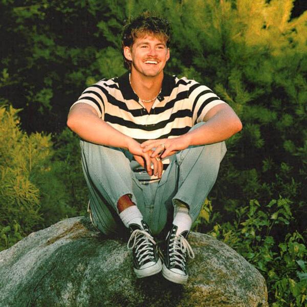 musician Forrest Frank sitting on a rock in the woods